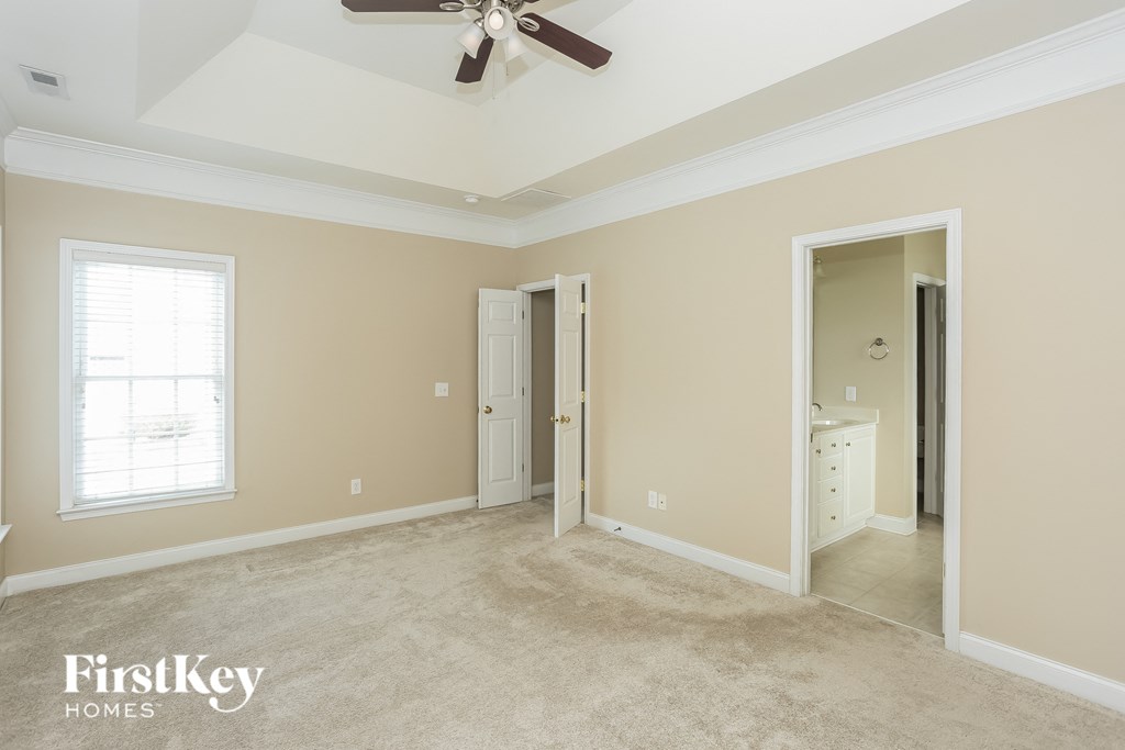 a bedroom with a ceiling fan and a door to a bathroom