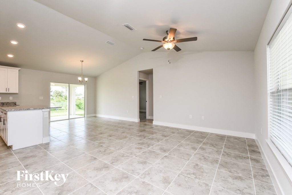 an empty living room with a ceiling fan and a kitchen