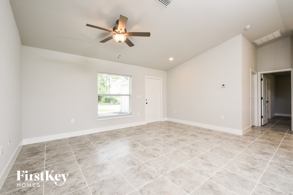 the spacious living room with tile flooring and a ceiling fan