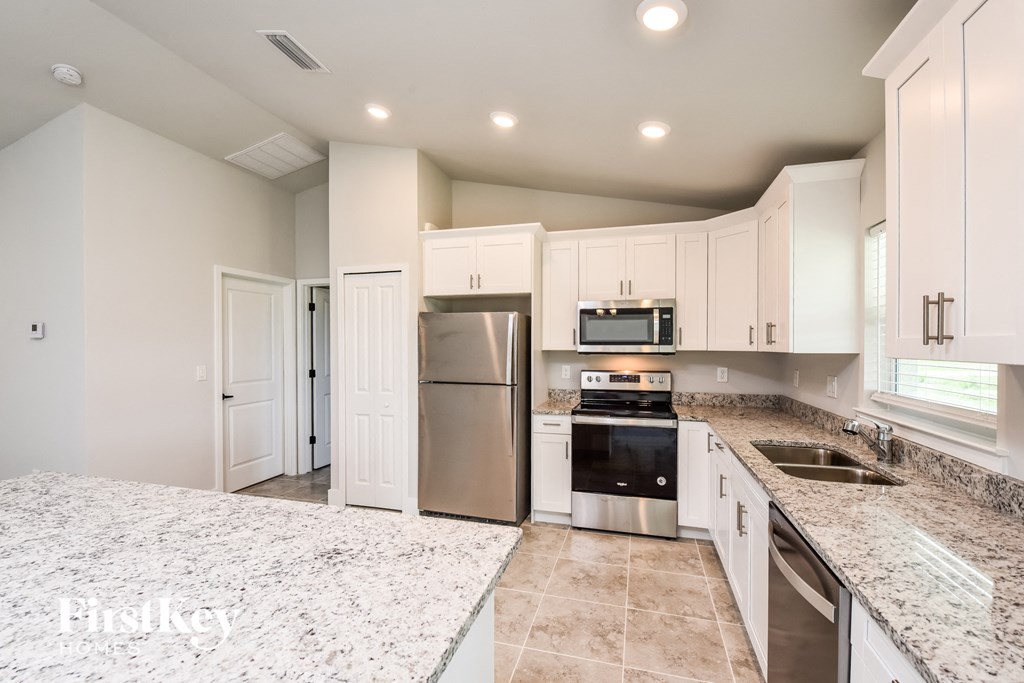 a white kitchen with granite counter tops and stainless steel appliances