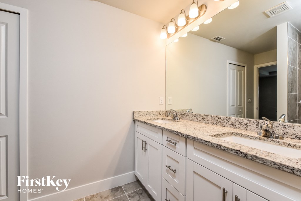 a bathroom with white cabinets and a sink and a mirror