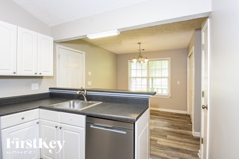 A kitchen with white cabinets and a black countertop.