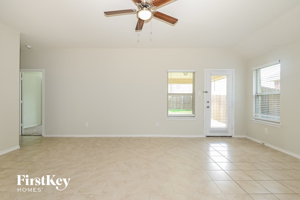 A spacious room with a ceiling fan and two doors.