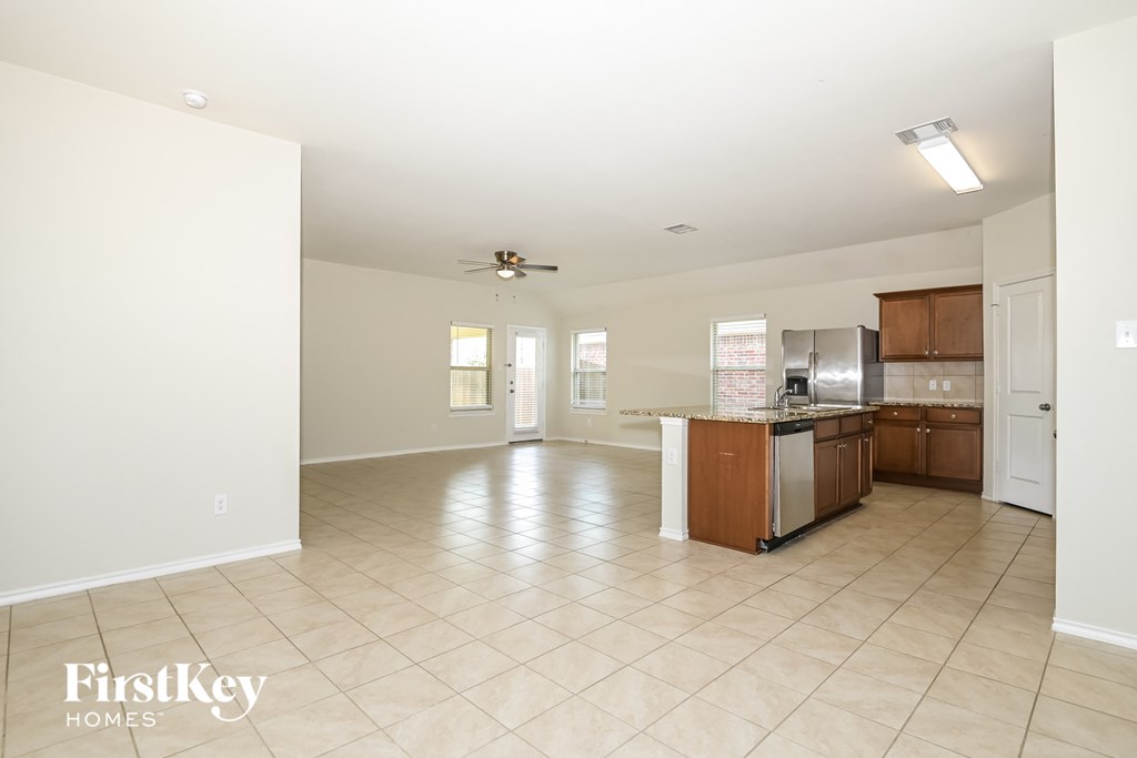 A spacious kitchen and living room with a tile floor and a ceiling fan.