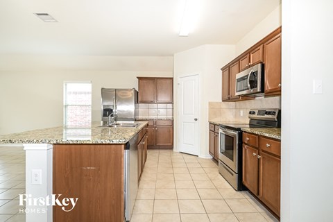A kitchen with wooden cabinets and a granite counter top.