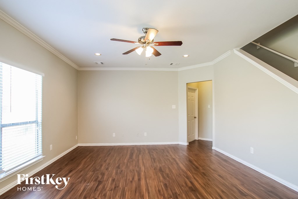 A spacious room with a ceiling fan and wooden flooring.
