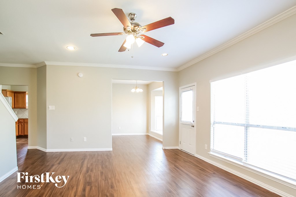 A spacious room with a ceiling fan and wooden floors.