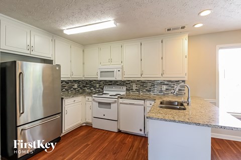 A kitchen with a stainless steel refrigerator and white cabinets.