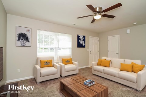 A living room with a white couch, two chairs, and a coffee table.