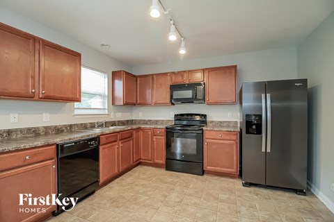 A kitchen with brown cabinets and black appliances.