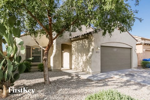 a white house with a garage door and a tree