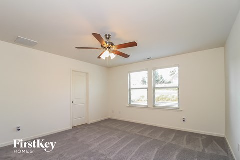 A room with a ceiling fan and a window with a view of trees.