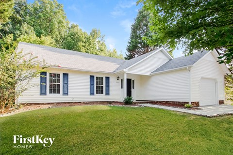 a white house with blue shutters and a green lawn