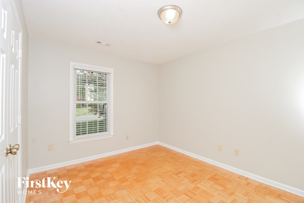 a bedroom with a hardwood floor and a window