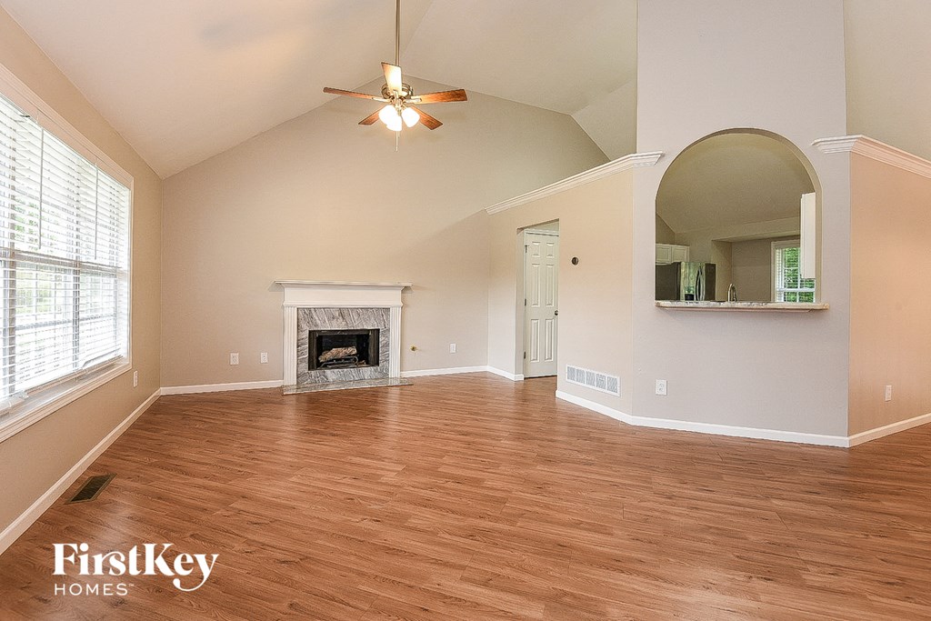 A spacious living room with wood flooring and a fireplace.