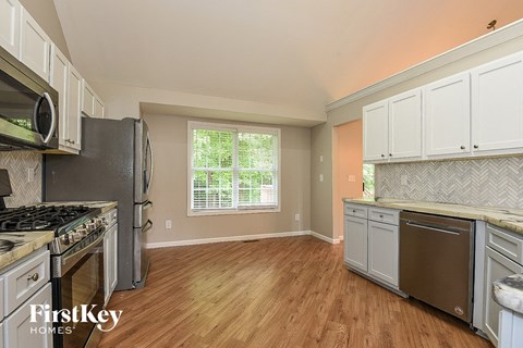 A kitchen with wooden floors and a stove top oven.