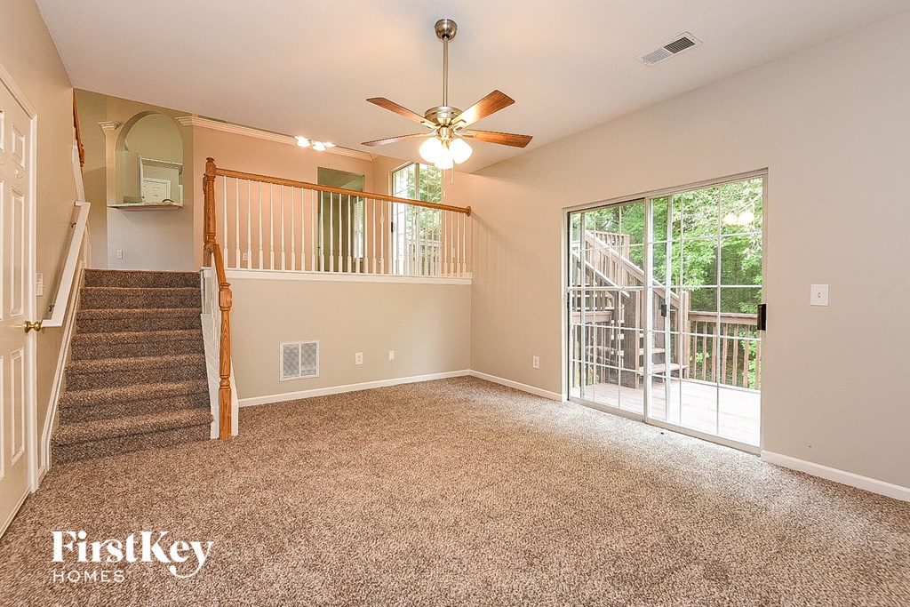 A spacious room with a staircase and a ceiling fan.