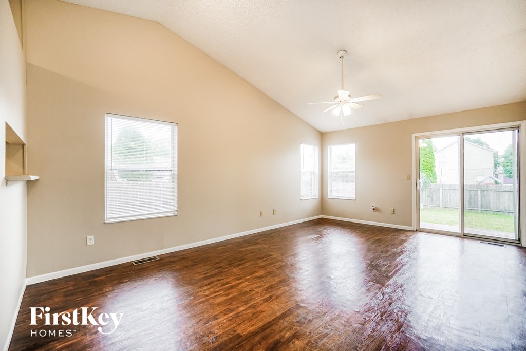 an empty living room with wood floors and a large window