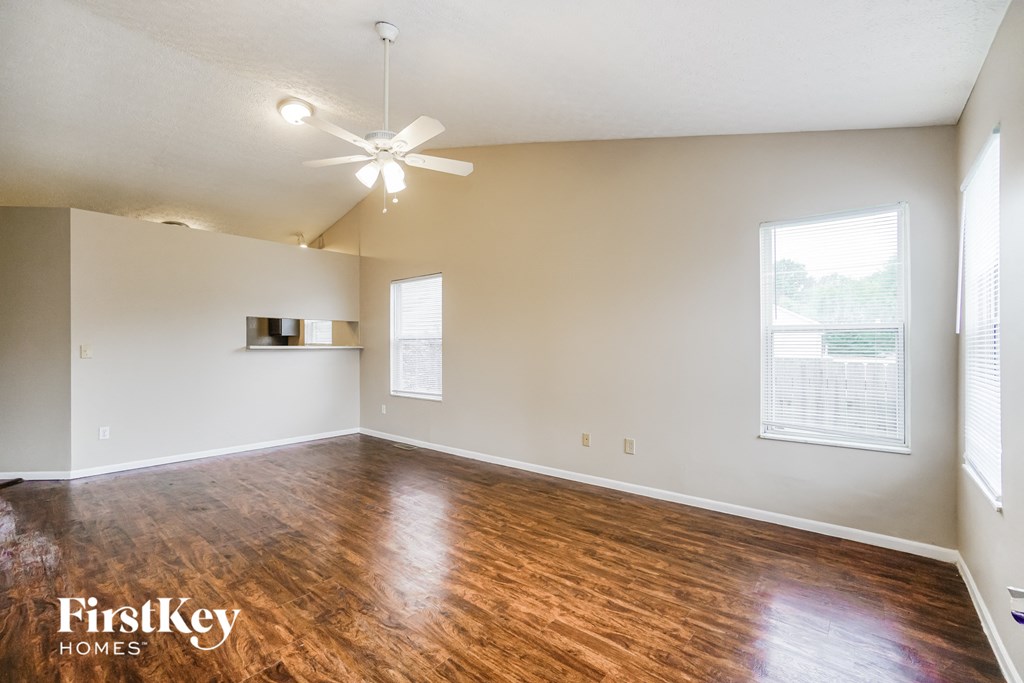 an empty living room with wood flooring and a ceiling fan