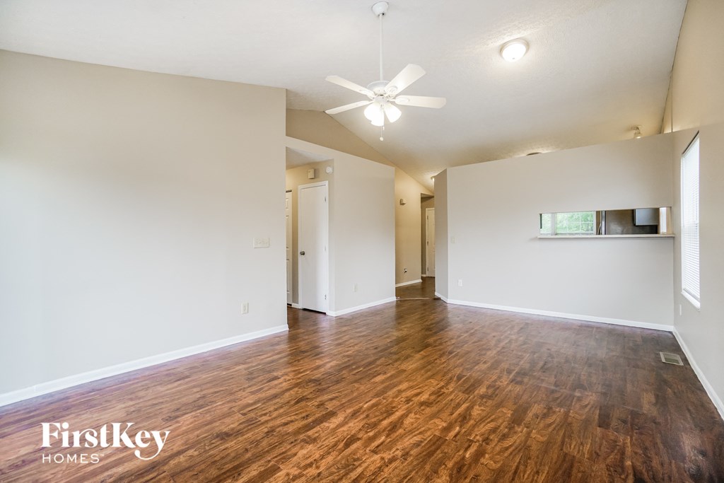 an empty living room with wood flooring and a ceiling fan