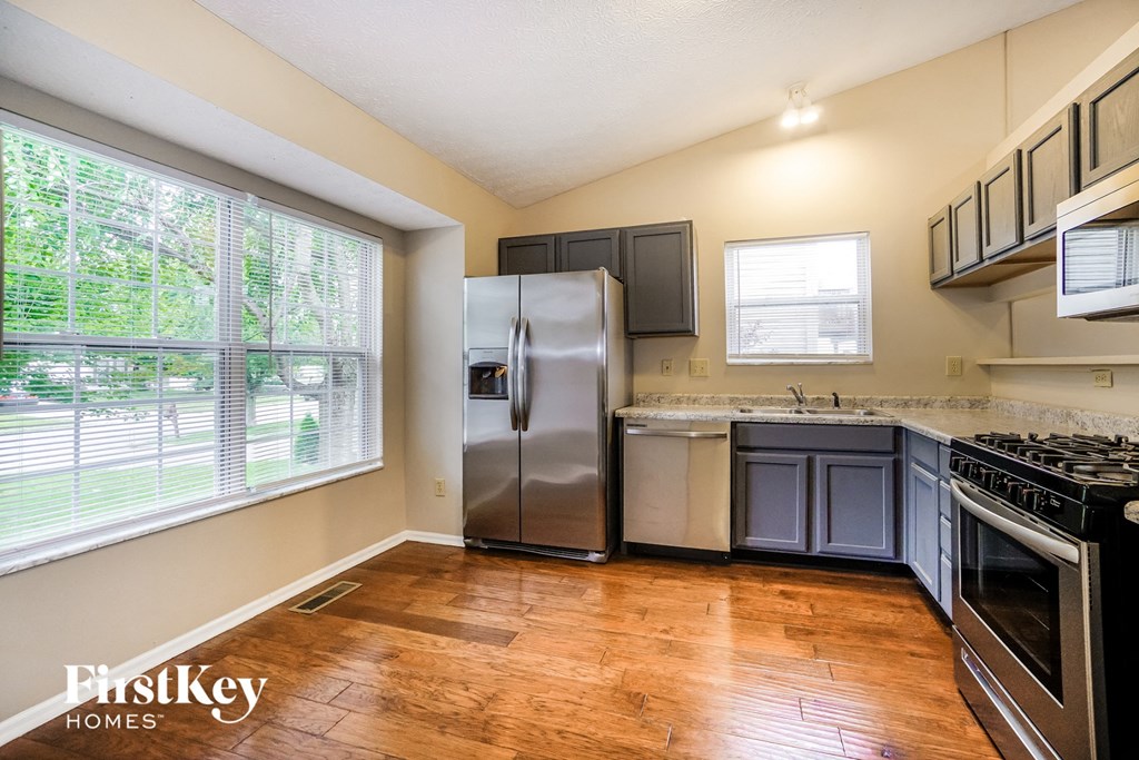 the kitchen has stainless steel appliances and a large window