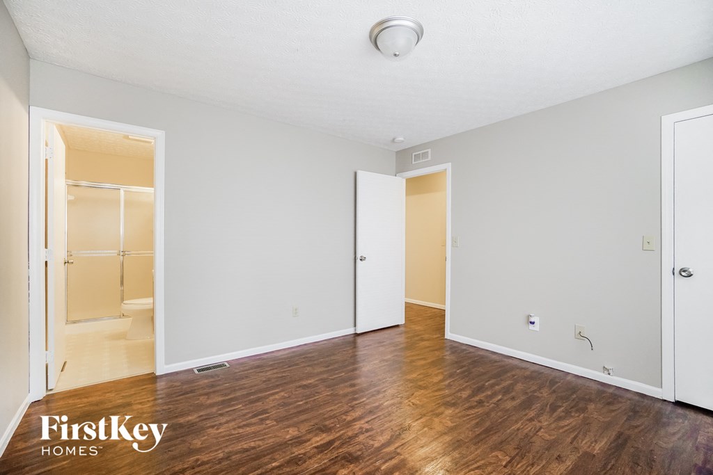 a living room with a hard wood floor and a door to a bathroom
