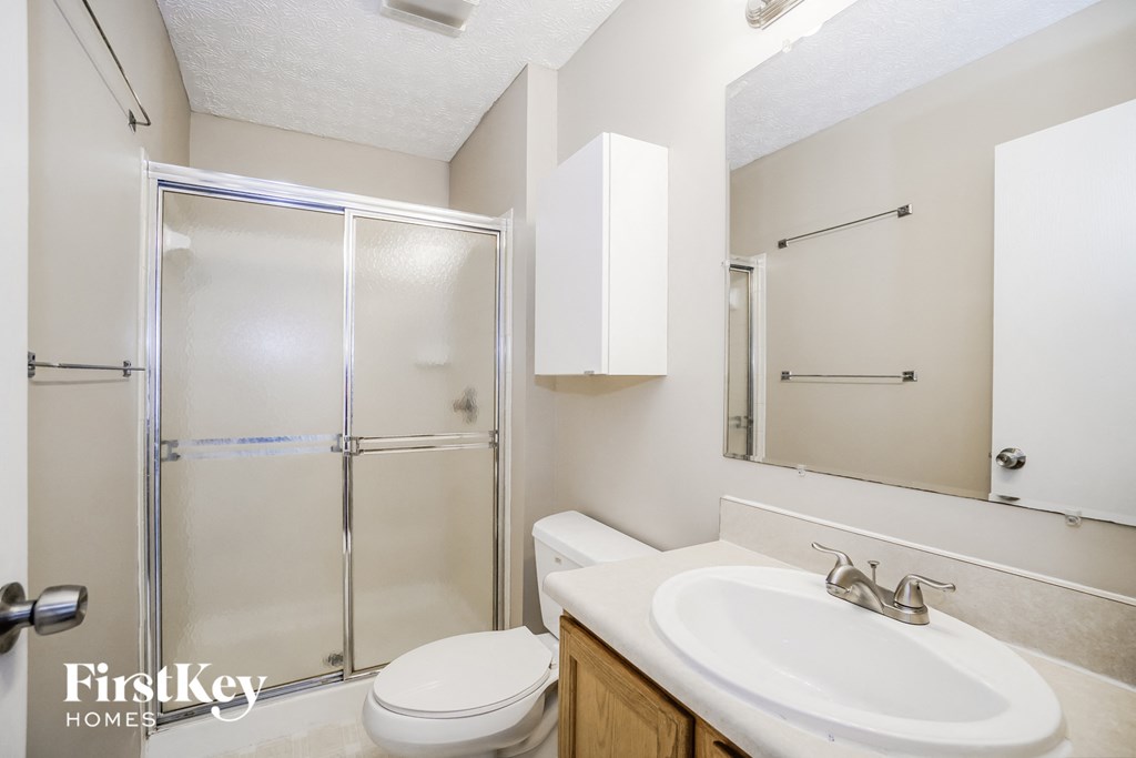 a bathroom with a shower sink and toilet and a mirror