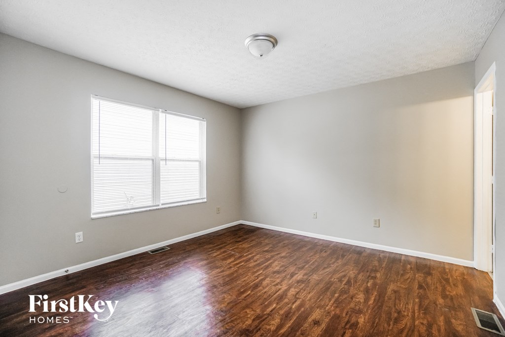 the spacious living room with hardwood flooring and a window