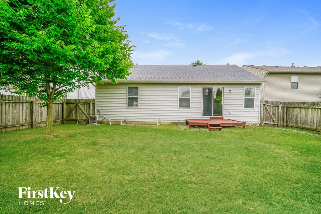 a backyard with a deck and a white house