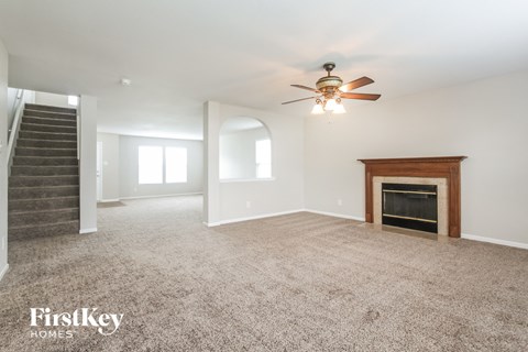 A spacious living room with a fireplace and a staircase.