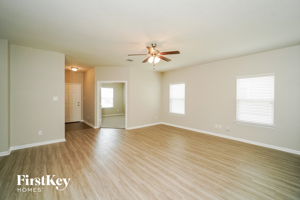 an empty living room with wood floors and a ceiling fan