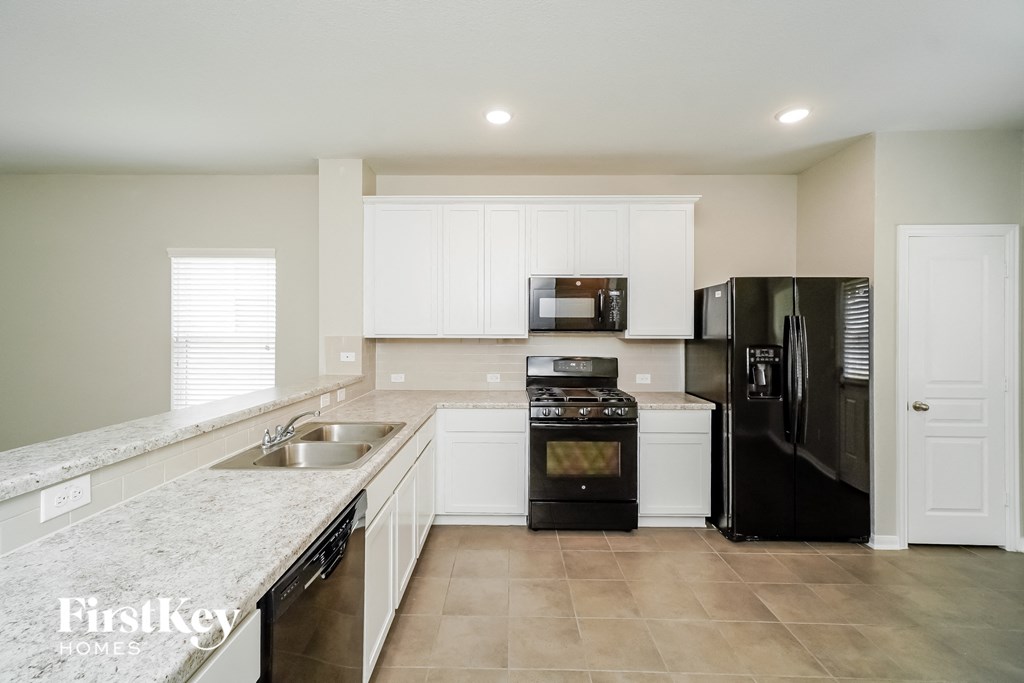 a kitchen with white cabinets and black appliances and a sink