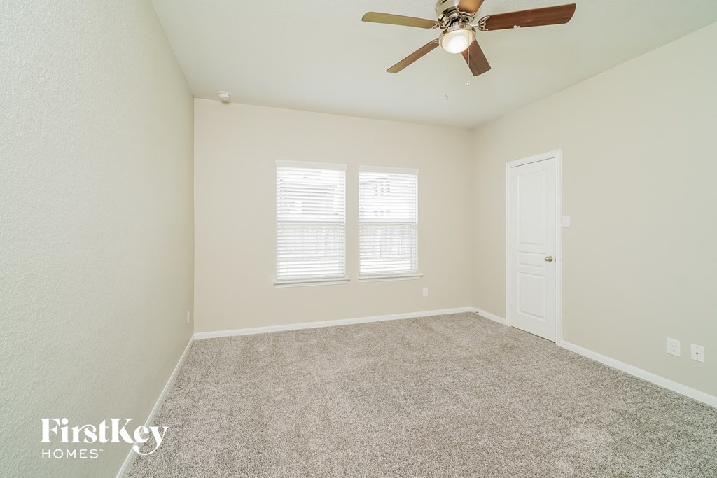 the spacious living room with ceiling fan and carpeting