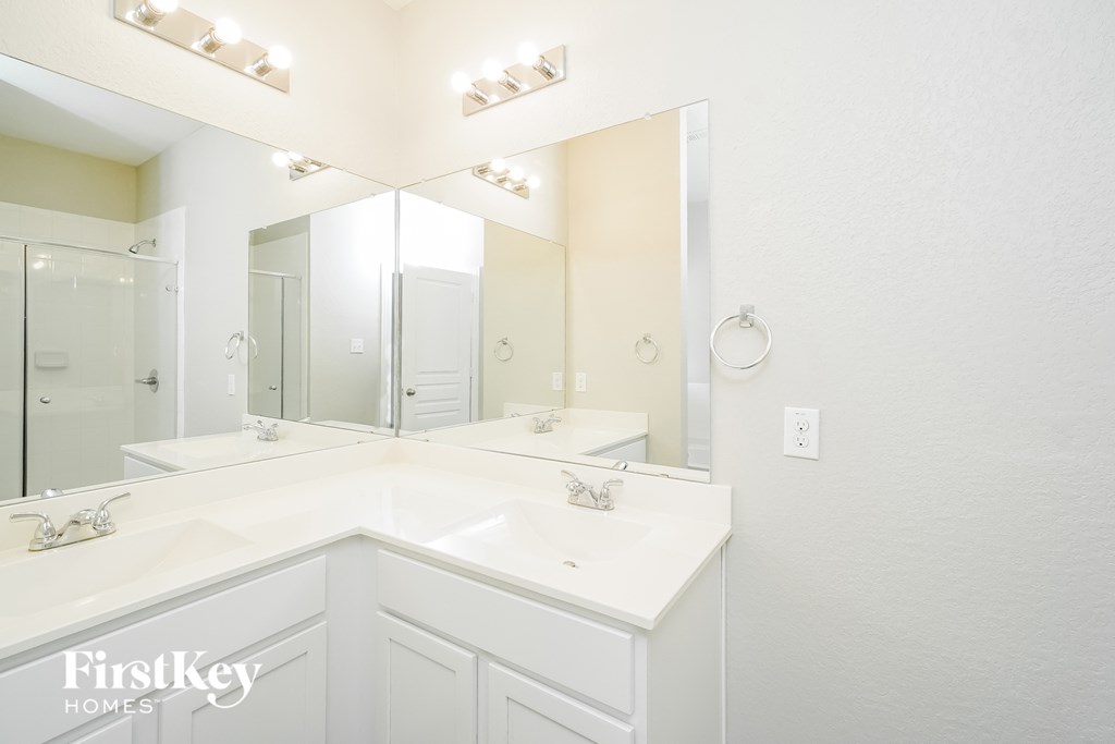 a white bathroom with two sinks and a large mirror