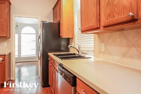 A kitchen with wooden cabinets and a black refrigerator.