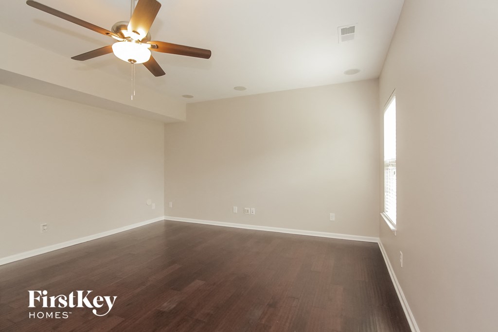 the spacious living room with wood flooring and a ceiling fan