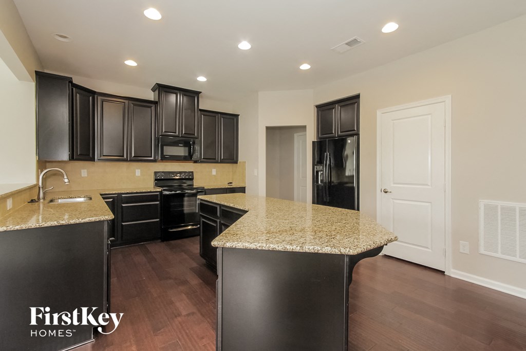 a kitchen with black cabinets and granite counter tops and black appliances