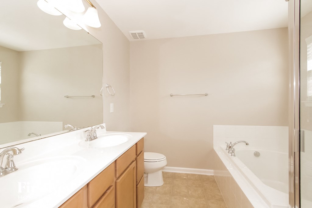 a bathroom with two sinks and a tub and a toilet