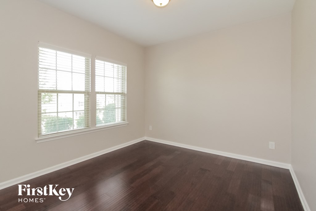 the living room of an empty house with wood flooring and two windows