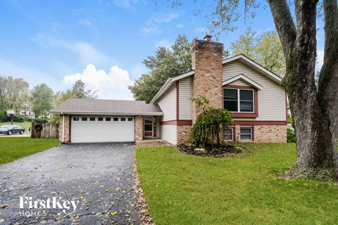 A house with a garage and a tree in front.