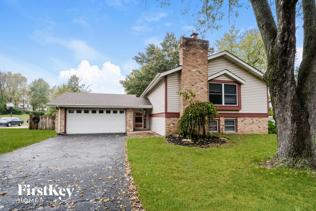 A house with a garage and a tree in front.