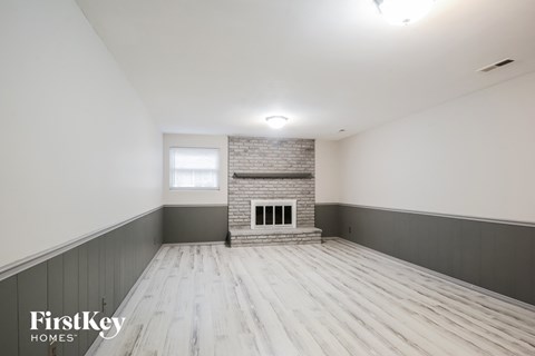 A spacious room with wooden flooring and a brick fireplace.