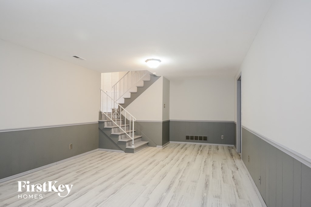 A spacious room with a staircase and wooden flooring.