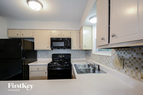 A kitchen with a black stove top oven and a black refrigerator.