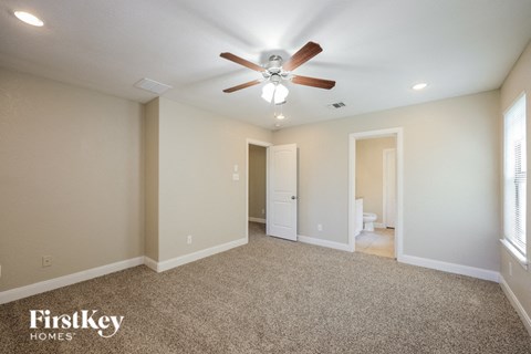 a spacious living room with carpet and a ceiling fan