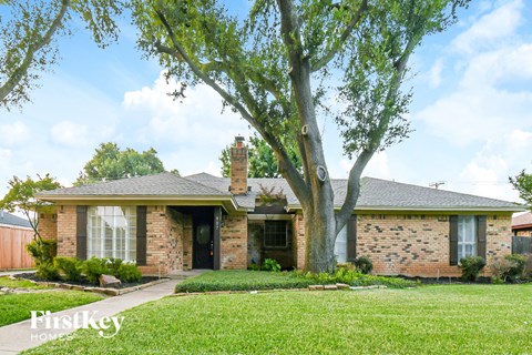 a brick house with a large tree in front of it