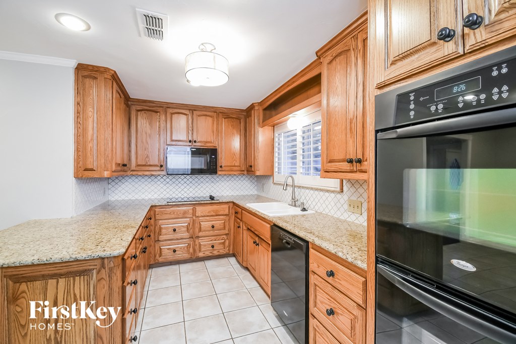 a kitchen with wooden cabinets and granite counter tops and black appliances