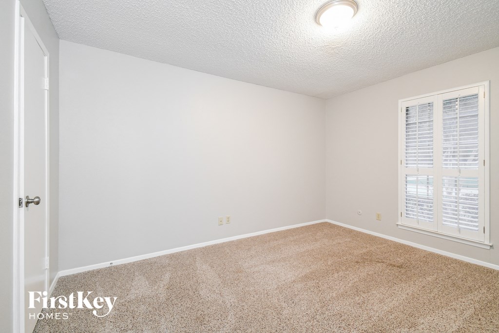 a bedroom with white walls and carpet and a window