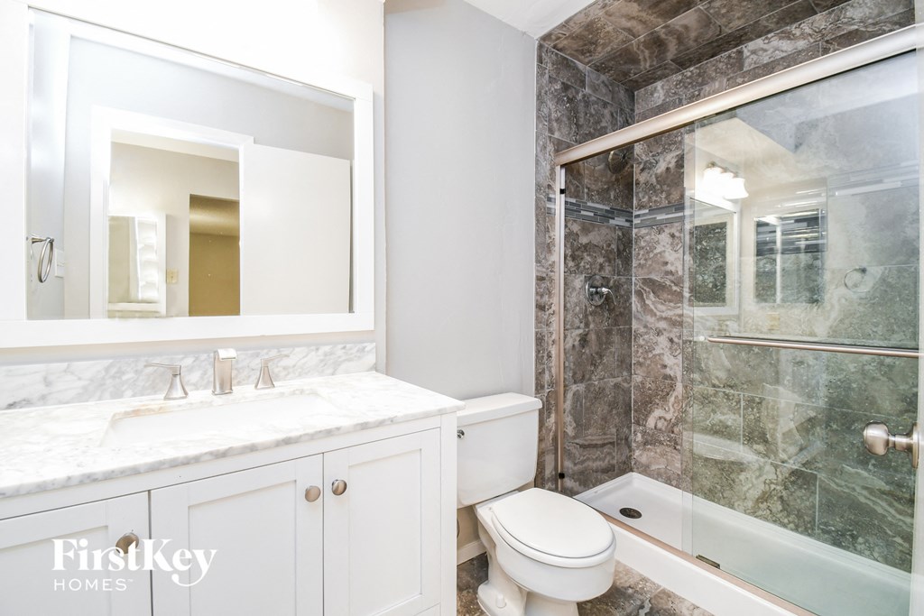 a bathroom with a shower toilet and sink and a mirror