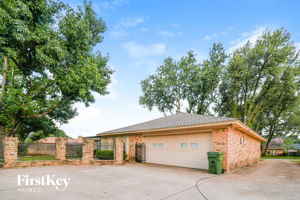 a brick house with a driveway and a fence
